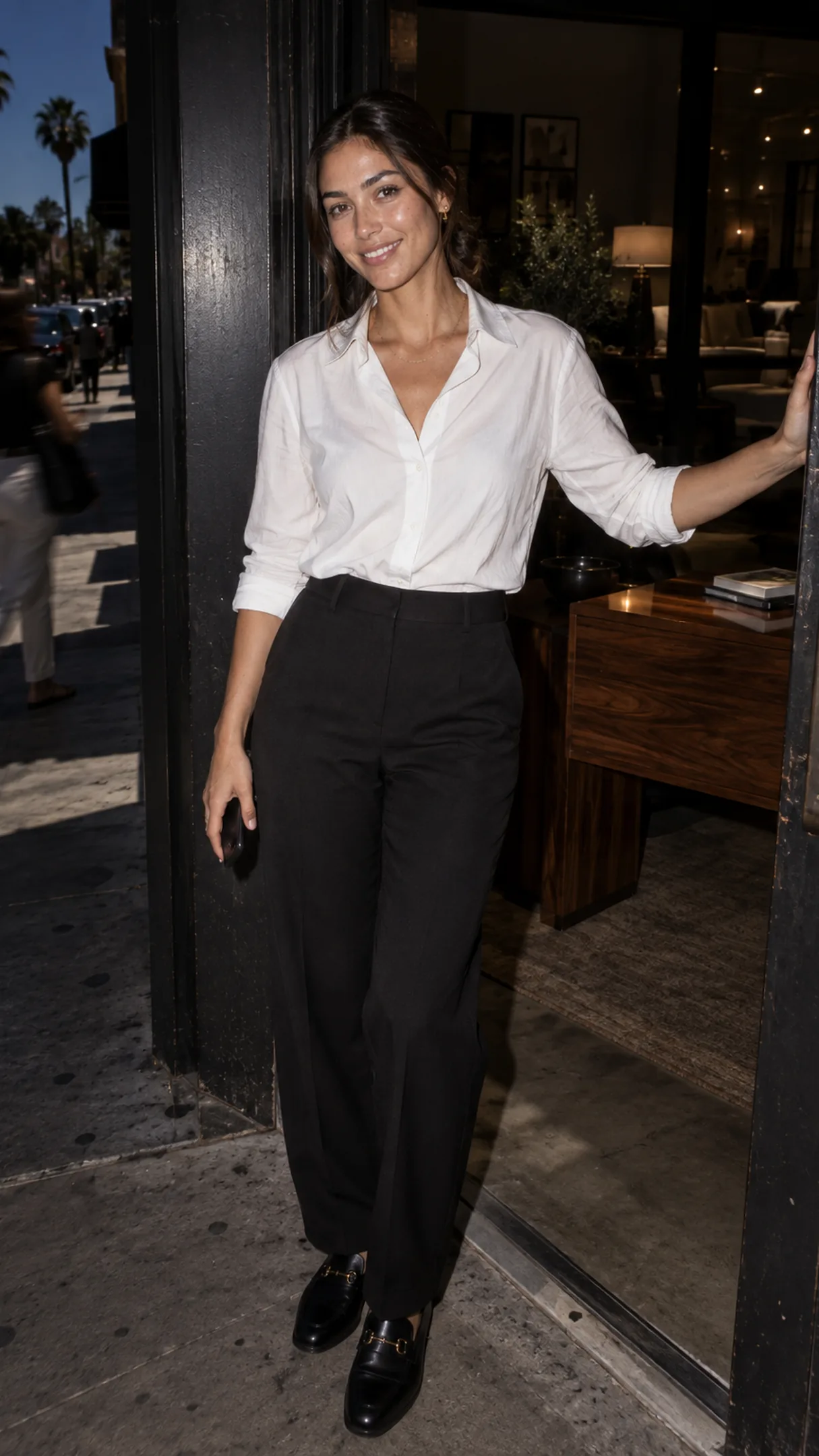 A founder in a furniture showroom's doorway, one hand on the door — her Page's inbox.